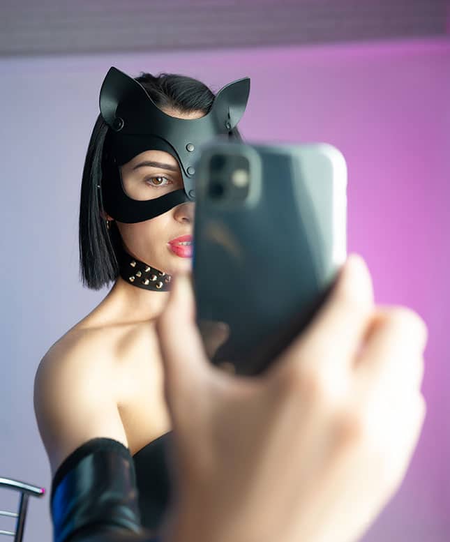 Frau mit lederner Katzenmaske macht Selfie