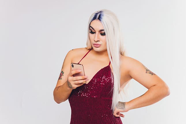 Blondes TS-Girl in rotem Kleid tippt am Smartphone